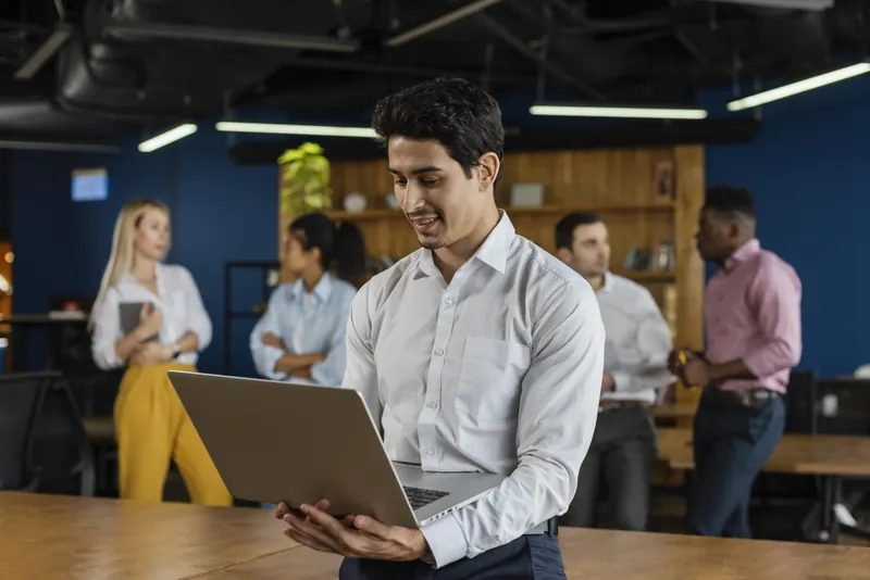 Corporate team collaborating around a laptop in a modern office