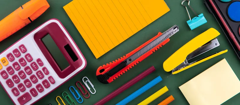 Calculator, sticky notes, cutter and highlighters on a green desk