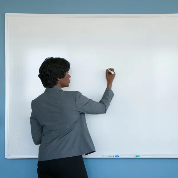 Professional writing on a whiteboard in a meeting room