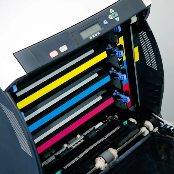 Open laser printer showing cyan, magenta, yellow and black toner cartridges
